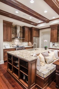 a large kitchen with wooden cabinets and marble counter tops, along with an island in the middle