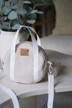 a white bag sitting on top of a table next to a potted plant