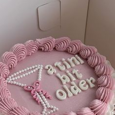 a pink cake with white icing and decorations