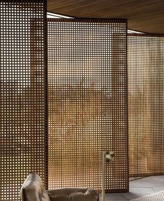 a room divider made out of wooden slats and metal rods with a leather chair in front