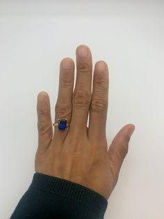 a person's hand with a ring on it and a blue stone in the middle