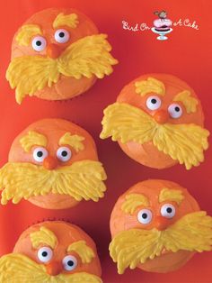 four cupcakes with yellow frosting decorated like sesame street characters and googly eyes