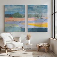 two paintings hang on the wall above a white chair in a room with wooden floors