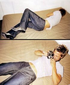 a man laying on top of a bed holding a camera