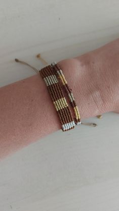 a woman's arm with two bracelets on it, one is brown and the other is white