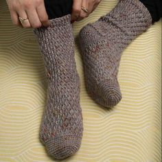 a woman sitting on top of a bed with her feet up in knitted socks