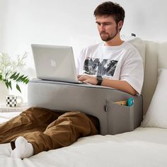 a man sitting on a bed with his laptop in front of him while he is working