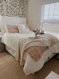 a white bed sitting next to a window covered in curtains and pillows on top of a carpeted floor