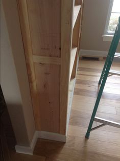 a ladder is next to a wooden door in a room with hard wood flooring