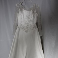 a white wedding dress hanging on a hanger with the back of it's jacket