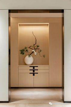 a vase with some flowers in it sitting on a table next to a wall mounted cabinet