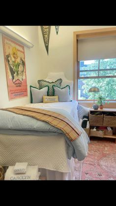 a bed sitting in a bedroom under a window next to a chair and table with two baskets on it