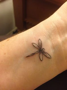 a small dragonfly tattoo on the wrist