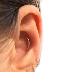 a woman's ear with two small gold hoops