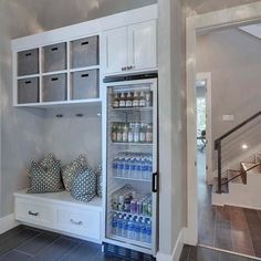 an open refrigerator in a kitchen next to some drawers and shelves with drinks on them