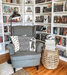 a living room filled with lots of books and furniture next to a white book shelf