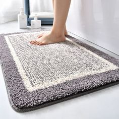 a person standing on top of a gray and white rug next to a bath tub