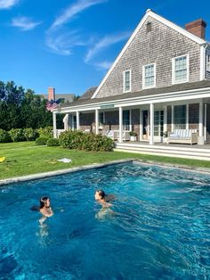 two people swimming in a pool next to a house