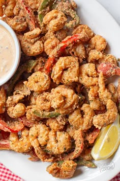 fried shrimp with dipping sauce on a white plate next to a red and white checkered tablecloth