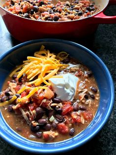 two bowls of chili and cheese soup on a table