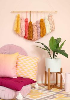 a bedroom with pink walls and colorful pillows on the bed, along with hanging tassels