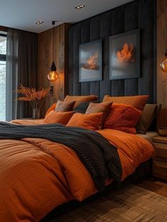 a bed with orange sheets and pillows in a bedroom next to a large window that looks out onto the woods