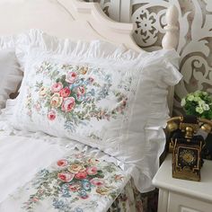 a white bed topped with lots of pillows next to a night stand and telephone on top of a table