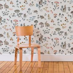 a wooden chair sitting in front of a wall with mushrooms on it