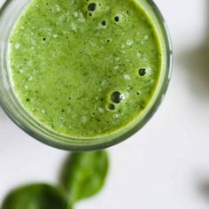 a green smoothie is in a glass on a table