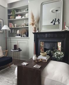 a living room filled with furniture and a fire place next to a wall mounted mirror