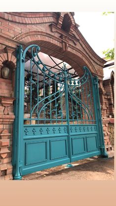 an ornate iron gate is shown in front of a brick wall and stone pillars with arched doorways