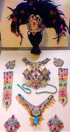 an assortment of jewelry is displayed on a white table with a black vase in the background