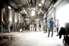 two people are standing in front of some metal tanks and looking at something on the floor