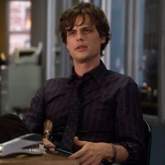 a young man sitting at a table with a tie on and looking off to the side