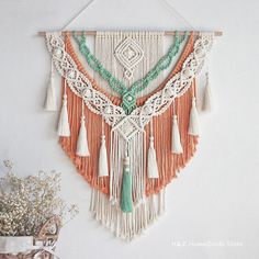 an orange and white wall hanging with tassels, beads and other things on it