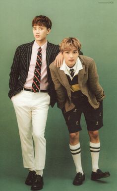 two young men standing next to each other in shorts and sweaters with ties on