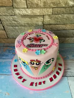 a birthday cake decorated with cartoon characters on the top and bottom tier, sitting on a table