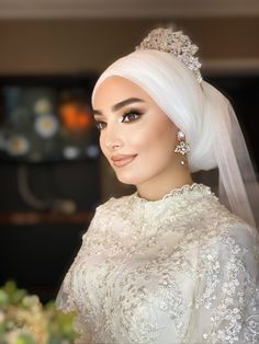 a woman with white hair wearing a veil and tiara, posing for the camera