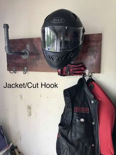 a motorcycle helmet hanging on the wall next to a leather jacket rack with two jackets