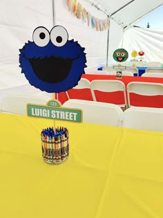 a sesame street sign and some crayons in front of a table with chairs