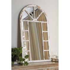 an old window mirror sitting on top of a mantle next to a potted plant