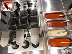 several different types of utensils and sauces on a stainless steel counter top