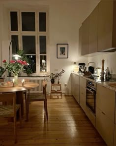 a kitchen with wooden floors and white walls is lit up by lights from the windows