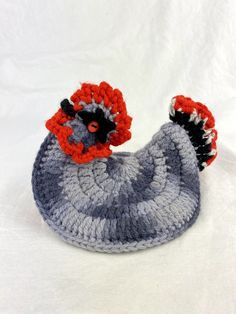 a crocheted gray and red rooster hat