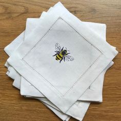 four white napkins with a bee embroidered on them