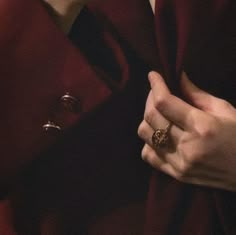 a woman in a red coat holding her hand out to the side with two rings on it