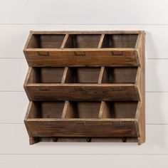 a wooden shelf with several bins on the top and two drawers below it, against a white wall