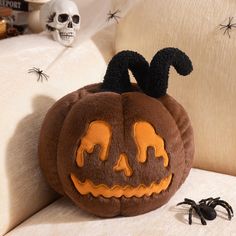 a stuffed pumpkin sitting on top of a white couch next to a black widow spider