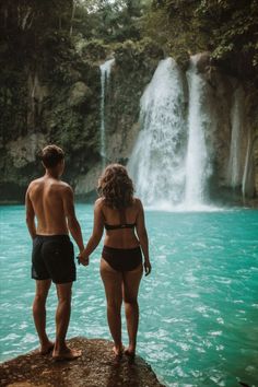 two people standing in front of a waterfall