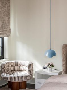 a bedroom with a bed, chair and lamp in it's corner next to a window